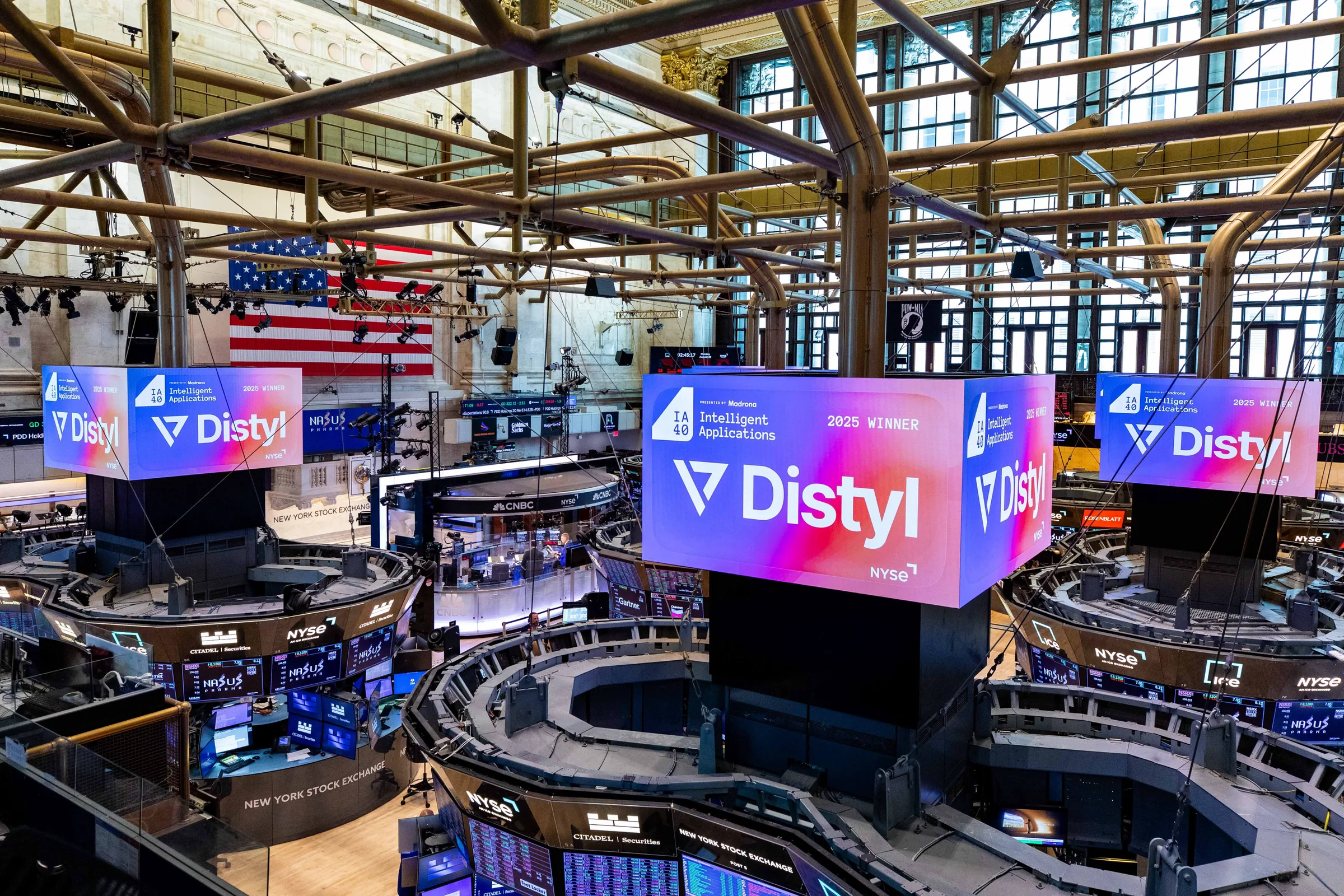 Distyl IA40 2025 winner graphics on the big screens above the New York Stock Exchange floor