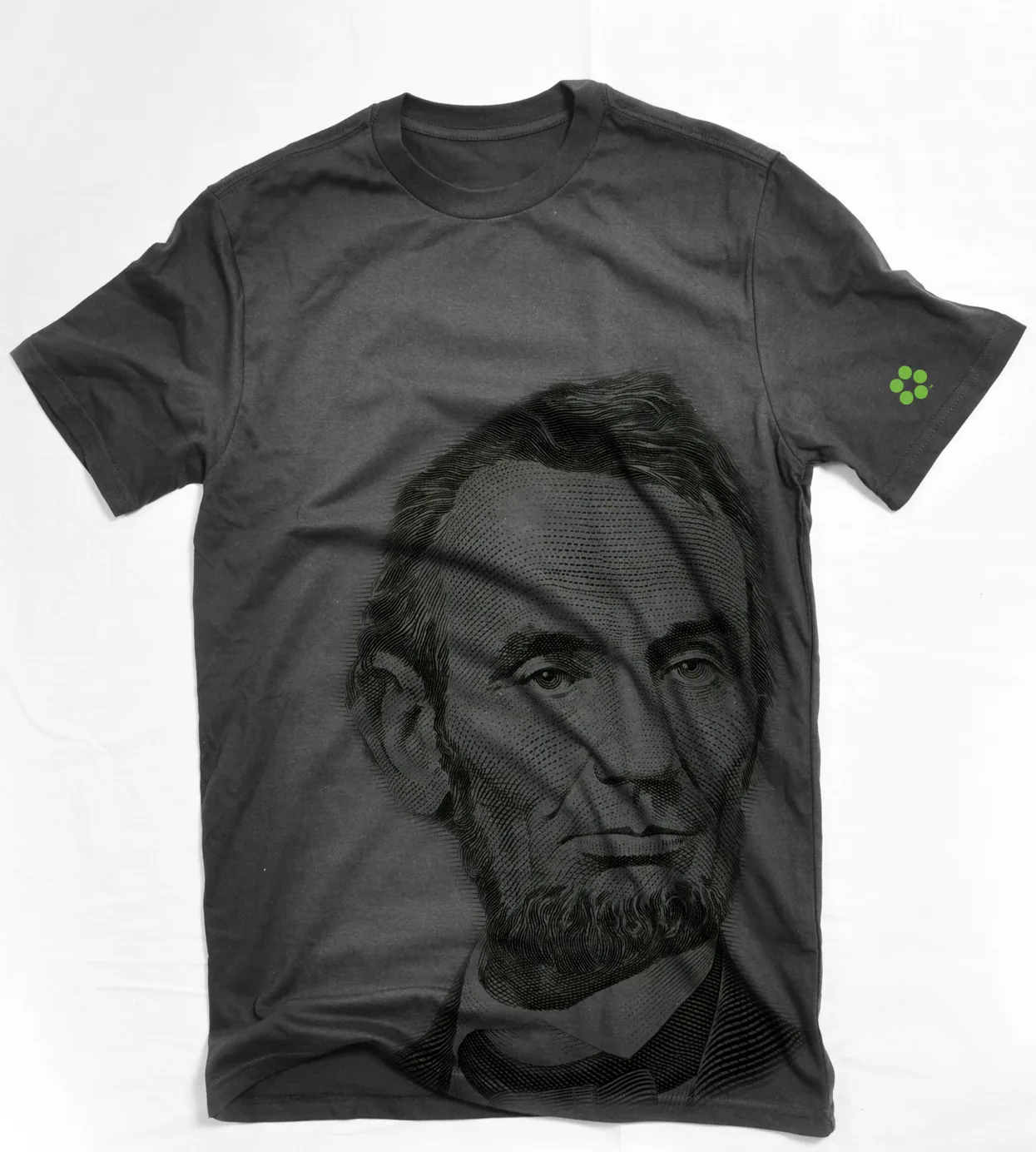 Charcoal tee with a giant engraved Lincoln portrait and a small green dot logo on the sleeve