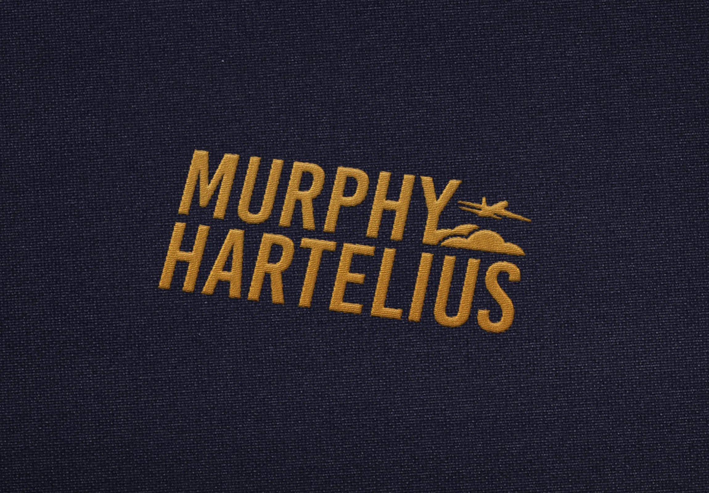 Murphy Hartelius logo embroidered in gold on navy fabric